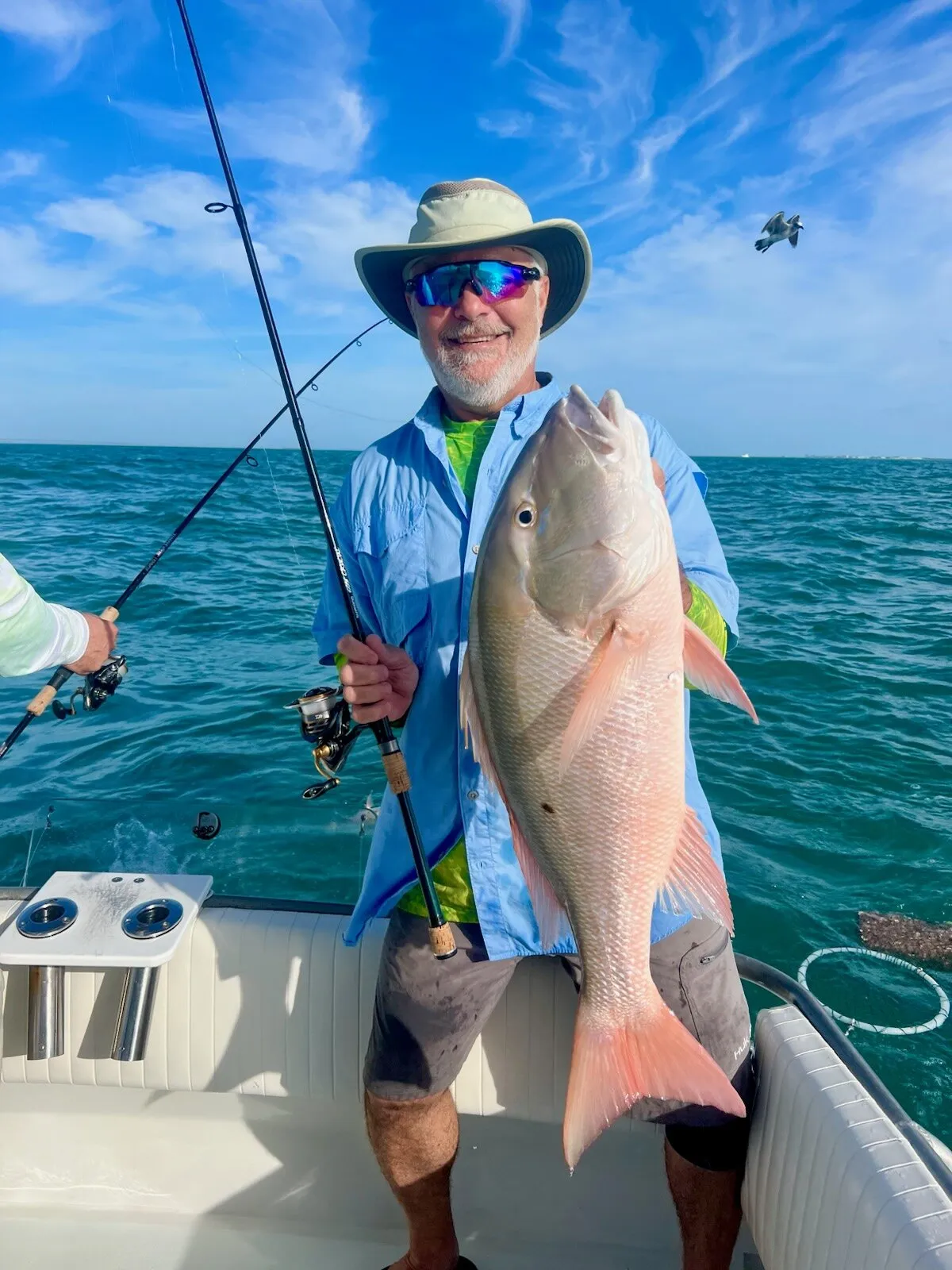 Angler in a sun hat with a mutton snapper